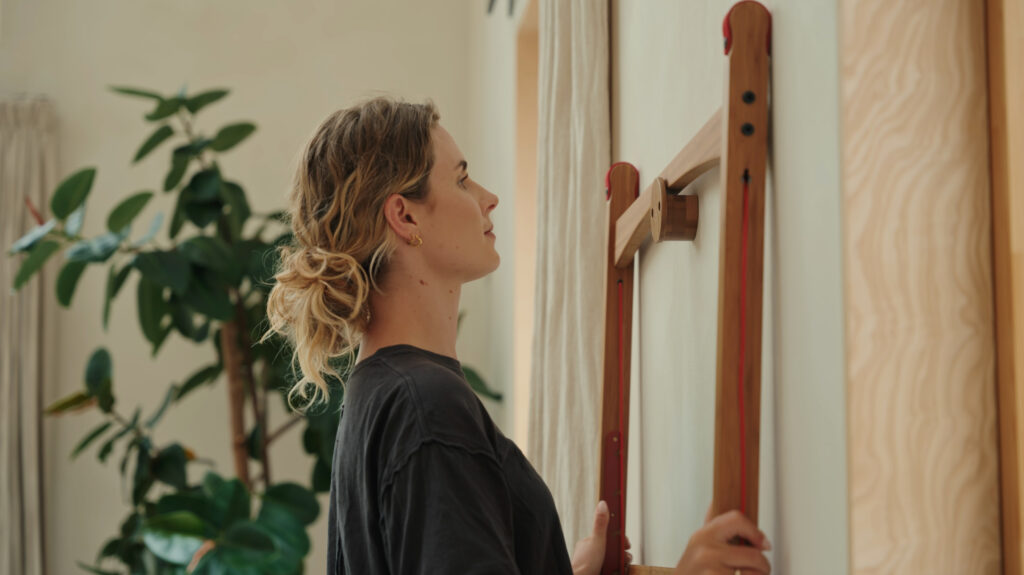 Leandesk bamboo folding desk stored flat on a wall hanger in a hallway — disappearing desk solution for hybrid workers in small UK homes