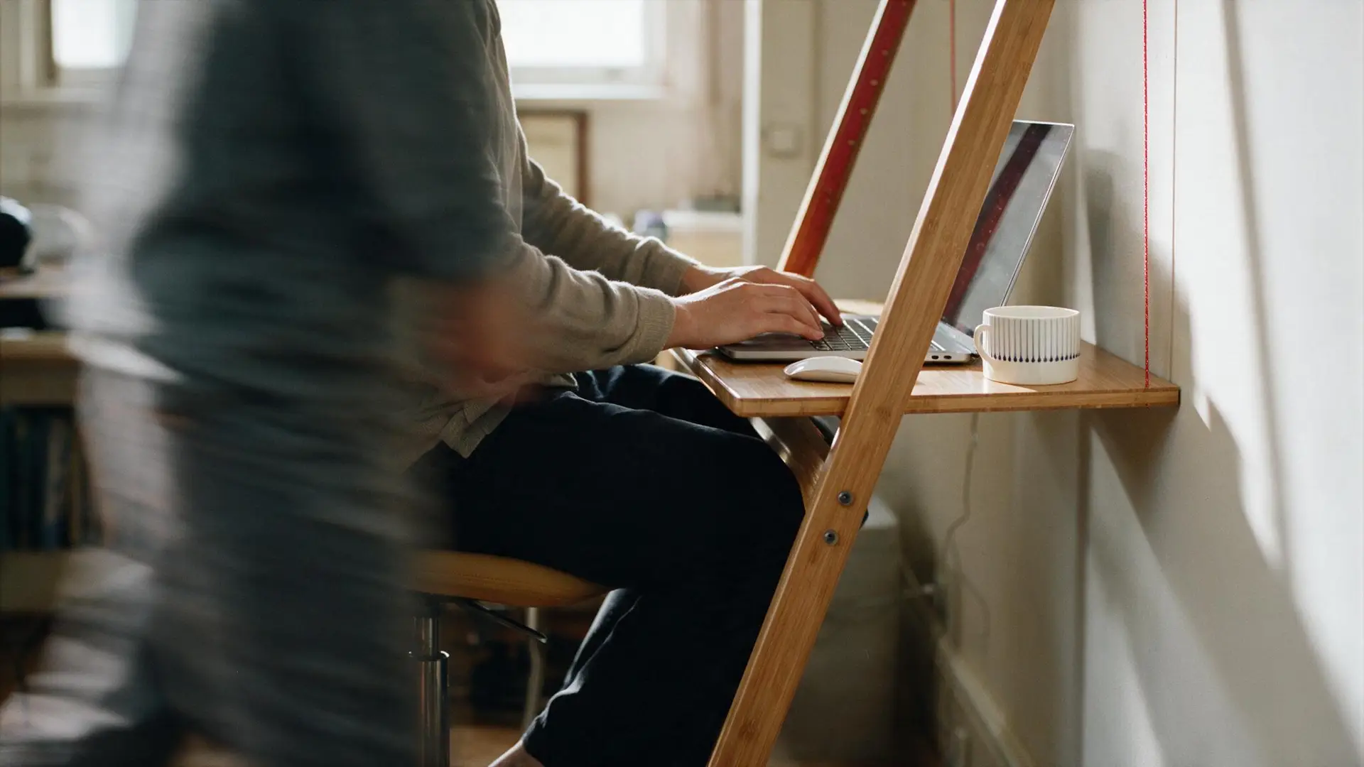 A person working on a hidden home office setup using leandesk folding desk.